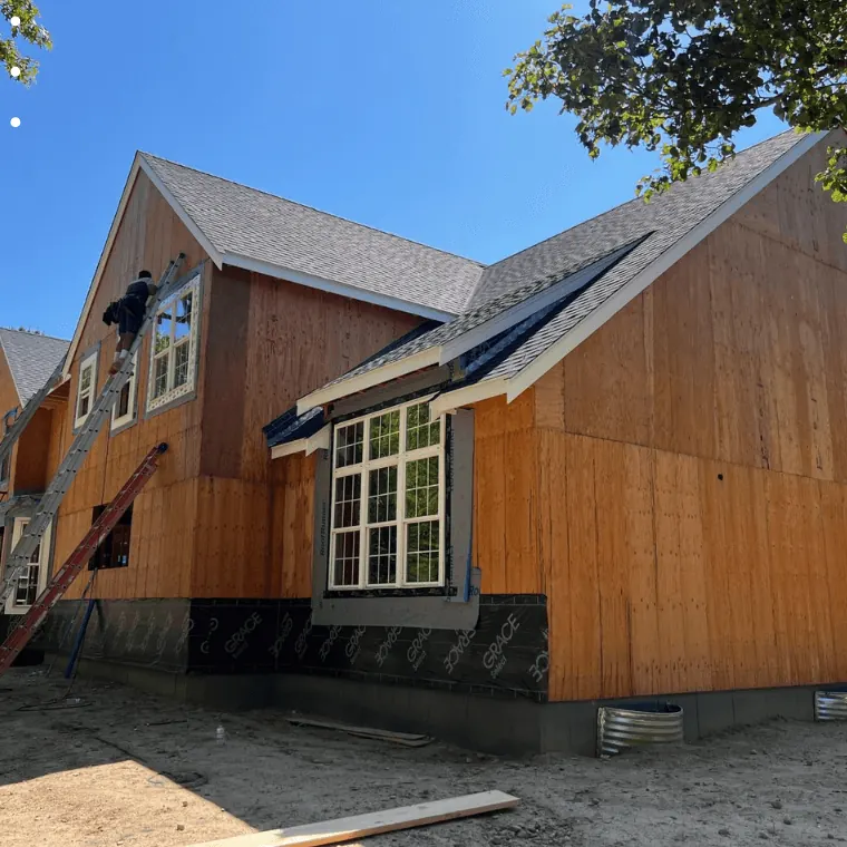 Crew installing wood siding and new windows on a house