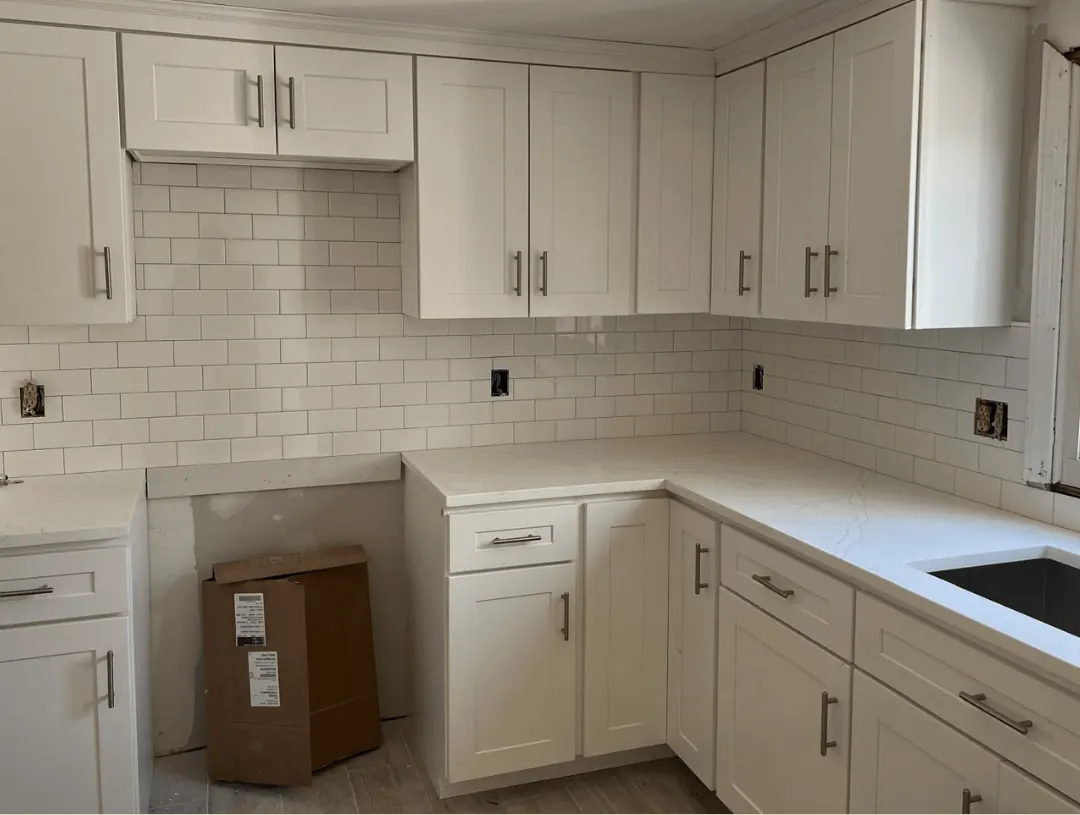 The same kitchen finished, with white cabinets, quartz counters and subway tile